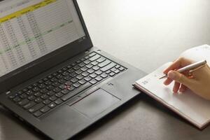 schot van een vrouw werken Aan de laptop tonen een excelleren vel Aan de scherm met bank lening afschrijvingen tafel. financiën foto