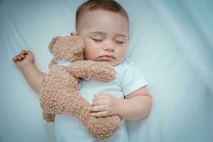 zoet baby dutten met een speelgoed- beer foto