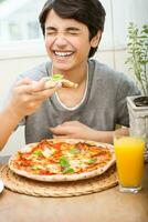 gelukkig tiener jongen aan het eten pizza foto