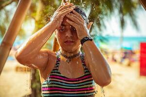 weinig meisje nemen douche Aan de strand foto