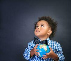 weinig schooljongen met wereldbol in handen foto