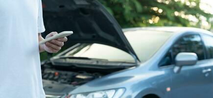 afbreken, gebroken auto, reparatie. Mens toepassingen mobiel telefoon controleren verzekering premies door toepassing ten gevolge naar auto ongeluk . vind garage naar krijgen auto gemaakt gedurende land tour, aan het wachten voor helpen, noodgeval. foto