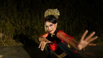 een balinees danser dansen onder de stadium lichten welke hoogtepunt haar rood jurk en creëren een elegant zichtbaar foto