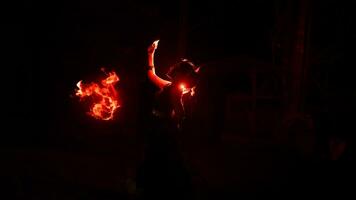 de silhouet van een vrouw danser Holding sieraden in de donker van nacht is lit door de licht van een brandend brand foto