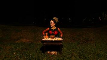 een vrouw danser presteert een ritueel dat creëert een magisch en mystiek atmosfeer in voorkant van bloem aanbiedingen foto