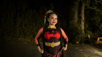 een Indonesisch danser straalt uit charme dat trekt aan de aandacht van de publiek gedurende de prestatie met haar rood jurk foto