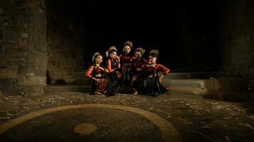 een groep van Indonesisch dansers zittend heel elegant terwijl vervelend rood jurken in een kasteel foto