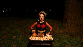 een vrouw danser presteert een ritueel dat creëert een magisch en mystiek atmosfeer in voorkant van bloem aanbiedingen foto