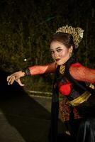 een Aziatisch danser in een rood kostuum poses heel flexibel Aan een stadium foto