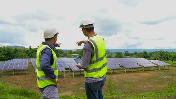 professioneel Aziatisch Mens ingenieur gebruik makend van digitaal tablet onderhouden zonne- cel panelen samen .technicus team werken Aan ecologisch zonne- boerderij. foto