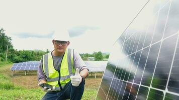 Aziatisch Mens ingenieur gebruik makend van digitaal tablet onderhouden zonne- cel panelen werken buitenshuis Aan ecologisch zonne- boerderij bouw. foto