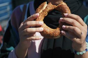 Dames Holding een Turks bagel simit buitenshuis foto