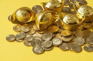 dichtbij omhoog visie van gouden baar en munten met geel Hoes achtergrond foto