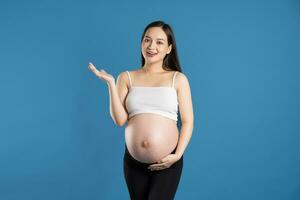 portret van zwanger Aziatisch vrouw, geïsoleerd Aan blauw achtergrond foto