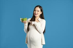 portret van zwanger Aziatisch vrouw, geïsoleerd Aan blauw achtergrond foto