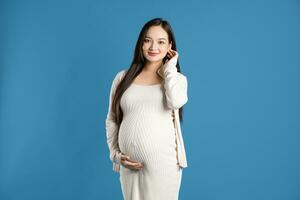 portret van zwanger Aziatisch vrouw, geïsoleerd Aan blauw achtergrond foto