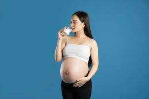 portret van zwanger Aziatisch vrouw, geïsoleerd Aan blauw achtergrond foto