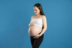 portret van zwanger Aziatisch vrouw, geïsoleerd Aan blauw achtergrond foto