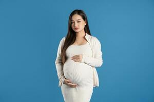 portret van zwanger Aziatisch vrouw, geïsoleerd Aan blauw achtergrond foto