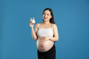 portret van zwanger Aziatisch vrouw, geïsoleerd Aan blauw achtergrond foto