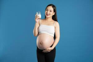 portret van zwanger Aziatisch vrouw, geïsoleerd Aan blauw achtergrond foto