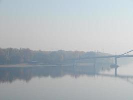 panorama van de herfststad in een waas van mist over de rivier foto