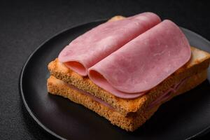 heerlijk belegd broodje met geroosterd brood brood, ham, tomaten, zout en specerijen foto