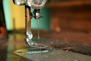 dichtbij omhoog naaien machine met naald- Aan hout tafel, antiek naaien machine met stof foto