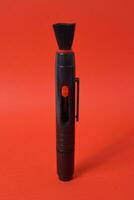 borstel en lens schoonmaakster pen voor camera geïsoleerd Aan rood achtergrond foto