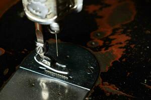 dichtbij omhoog naaien machine met naald- Aan hout tafel, antiek naaien machine met stof foto