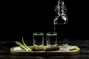 wodka en twee glazen en komkommers met spek en uien foto