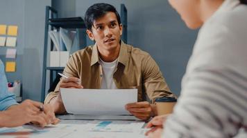 gelukkige jonge Aziatische zakenlieden en zakenvrouwen die brainstormen over een aantal nieuwe ideeën over het project aan zijn partner die samenwerken bij het plannen van successtrategie geniet van teamwork in een klein modern kantoor aan huis. foto