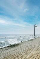 wit houten pier, blauw lucht, zee. wit banken Aan de pier. Nee mensen foto