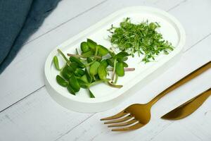 microgreens zonnebloem en luzerne met bestek Aan de tafel. gezond vitamines voedsel concept. foto
