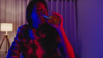 jonge azië dame bier drinken plezier gelukkig moment disco neon nacht feest evenement online viering via video-oproep in de woonkamer thuis. sociale afstand, quarantaine voor coronaviruspreventie. foto