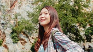 vrolijke jonge reiziger Aziatische dame met rugzak wandelen op het bergmeer. Koreaans tienermeisje geniet van haar vakantieavontuur en voelt zich gelukkig in vrijheid. levensstijl reizen en ontspannen in vrije tijd concept.