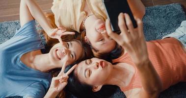 bovenaanzicht close-up groep Azië dames met geluk geniet van moment houd smartphone glimlachend neem herinneringen foto liggend op tapijt in de vloer woonkamer thuis. levensstijl activiteit quarantaine concept.