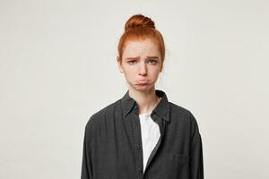 beledigd van streek verdrietig jong meisje gekleed in gewoontjes zwart shirt, Aan haar gezicht uitdrukking van belediging droefheid, lager lip steenbolk, beeldt af een wrok, geïsoleerd Aan wit achtergrond foto