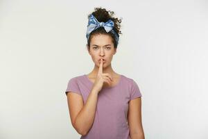 portret van jong vrouw kijken streng, houdt haar vinger Bij haar mond, een gebaar van stilte, naar houden een geheim, naar worden stil, over- wit achtergrond. mensen en emoties concept foto