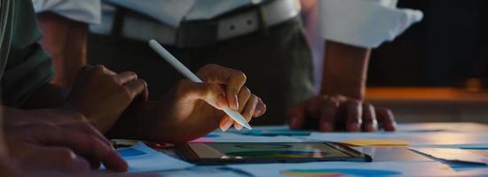 Azië zakenlieden en zakenvrouwen ontmoeten brainstormen ideeën collega's die samenwerken bij het plannen van successtrategie genieten van teamwork in nachtkantoor. panoramische bannerachtergrond met exemplaarruimte. foto