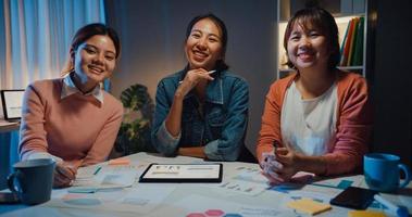millennial azië mensen ontmoeten brainstormideeën over nieuw papierwerk projectcollega's die samenwerken plannen successtrategie genieten van teamwork in een klein modern nachtkantoor. collega teamwerk concept. foto