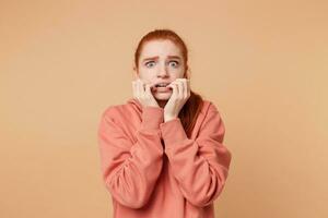 een vreselijk bang jong vrouw met angst staart Bij de camera, voelt Leuk vinden een slachtoffer ziet iets verschrikkelijk, houden handen in de buurt de mond bijt haar nagels wil naar verbergen, ontsnappen. foto