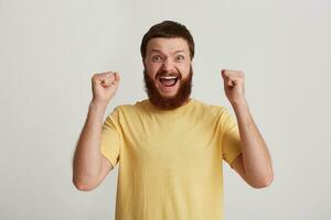 portret van vrolijk opgewonden jong Mens hipster met baard draagt geel t overhemd looks Vrolijk, geschreeuw en hebben pret geïsoleerd over- wit achtergrond foto