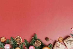 minimale creatieve platte lay van traditionele kerstcompositie en nieuwjaarsvakantieseizoen. bovenaanzicht winter kerstversiering op rode achtergrond met lege ruimte voor tekst. kopieer ruimtefotografie. foto