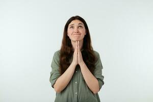 studio schot van van streek jong mooi bruin haren vrouw gekleed in gewoontjes kleren verhogen handen in bidden gebaar terwijl op zoek wanhopig omhoog, geïsoleerd over- wit achtergrond foto