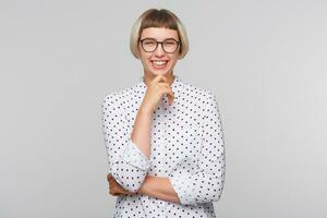 detailopname van vrolijk lief blond jong vrouw draagt polka punt overhemd en bril houdt handen gevouwen en lachend geïsoleerd over- wit achtergrond foto