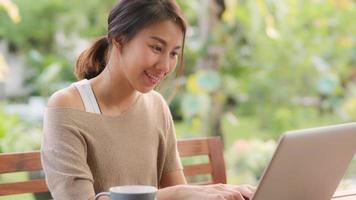 freelance aziatische vrouw die thuis werkt, zakelijke vrouw die 's ochtends op een laptop in de tuin zit. levensstijl vrouwen die thuis werken concept.