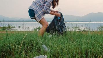 gelukkige jonge azië-activisten die plastic afval verzamelen op het strand. Koreaanse vrouwelijke vrijwilligers helpen de natuur schoon te houden en vuilnis op te halen. concept over milieubehoud vervuilingsproblemen.