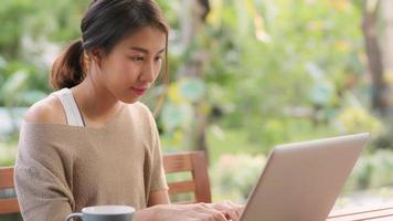 freelance aziatische vrouw die thuis werkt, zakelijke vrouw die 's ochtends op een laptop in de tuin zit. levensstijl vrouwen die thuis werken concept.