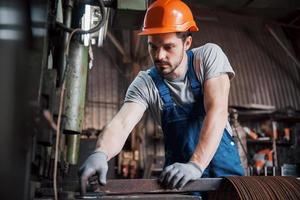 portret van een jonge werknemer met een helm in een grote afvalrecyclingfabriek. de ingenieur bewaakt het werk van machines en andere apparatuur; foto